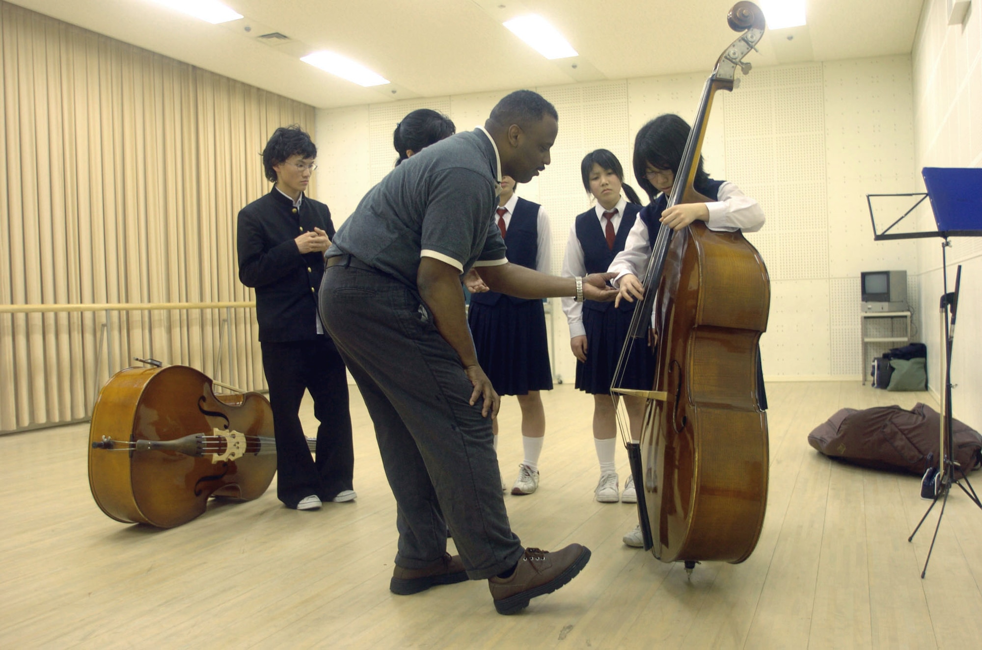 MATSUYAMA, Japan -- Staff Sgt. Terry Grace shows Japanese high-school students proper fingering techniques on an acoustic bass instrument during a music clinic here April 15.  Sergeant Grace is a bass player with the U.S. Air Force Band of the Pacific-Asia at Yokota Air Base, Japan.  (U.S. Air Force photo by Master Sgt. Val Gempis)