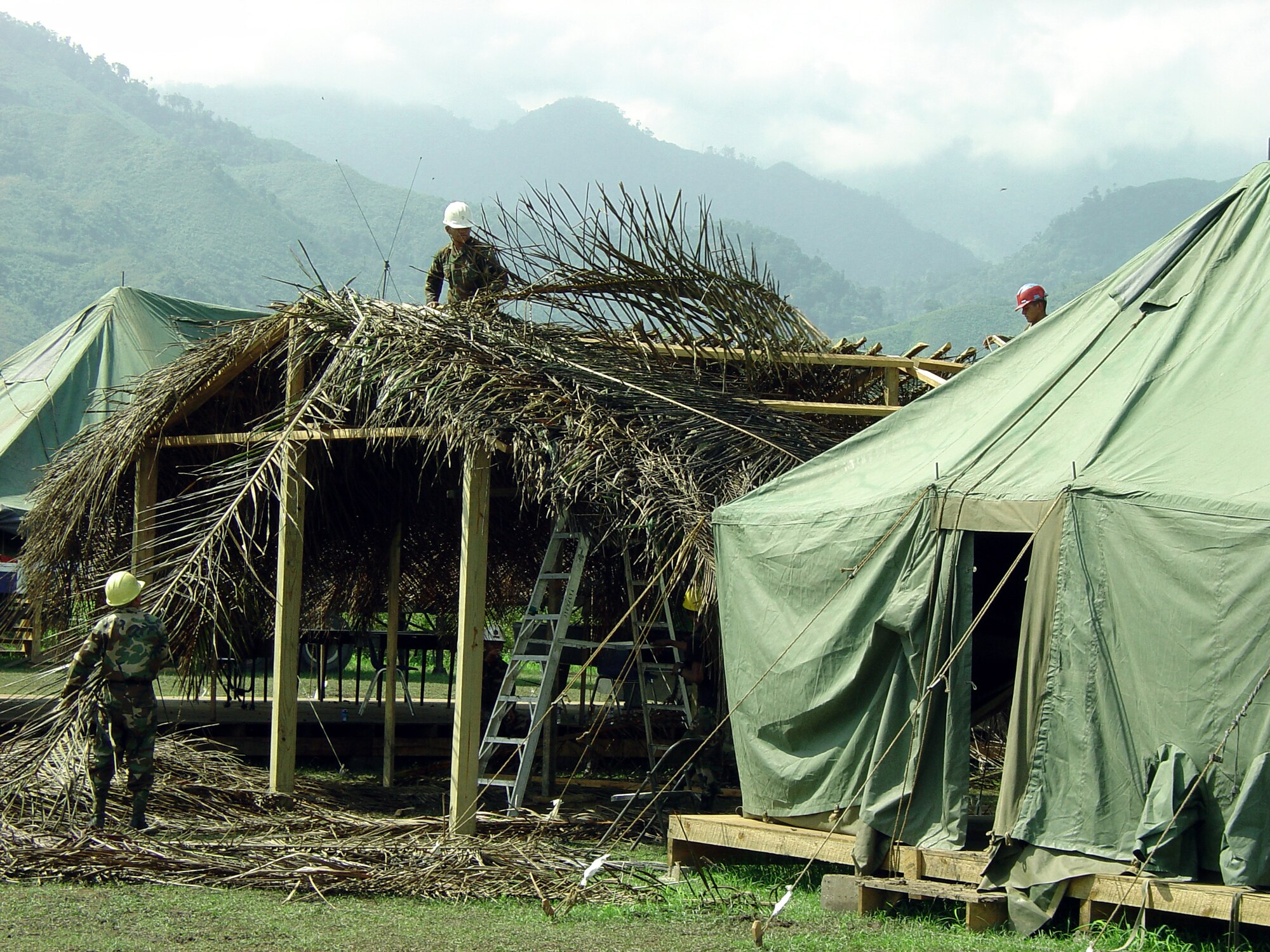SABA, Honduras -- Honduran soldiers place tree thatch on the roof of the camp's morale, welfare and recreation tent.  The Honduran army, U.S. Army, Puerto Rican Army National Guard and the 934th Civil Engineer Squadron shared the camp during an exercise.  The main focus of the exercise was to build local schools, medical clinics and provide medical support to local villages.  (U.S. Air Force photo by Tech. Sgt. Robert Walz)