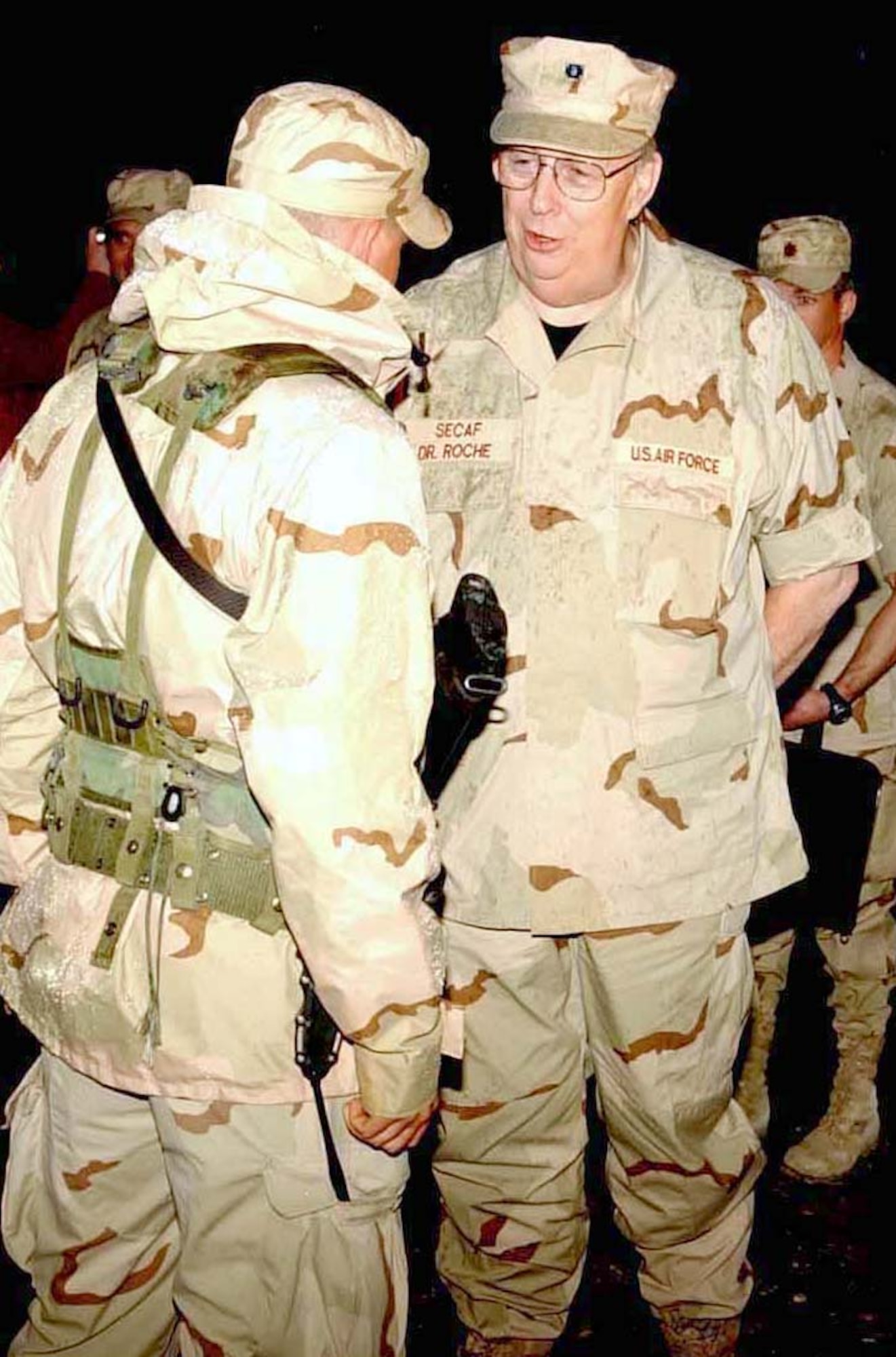 BAGRAM AIR BASE, Afghanistan -- Secretary of the Air Force Dr. James G. Roche pauses at the gate to Camp Cunningham, where he received a briefing from Airman 1st Class Donald Wilburn.  Secretary Roche met with the men and women of the 455th Expeditionary Operations Group during his visit here April 16.  Airman Wilburn is assigned to the 455th Expeditionary Security Forces Squadron.  (U.S. Air Force photo by Master Sgt. Jeff Szczechowski)