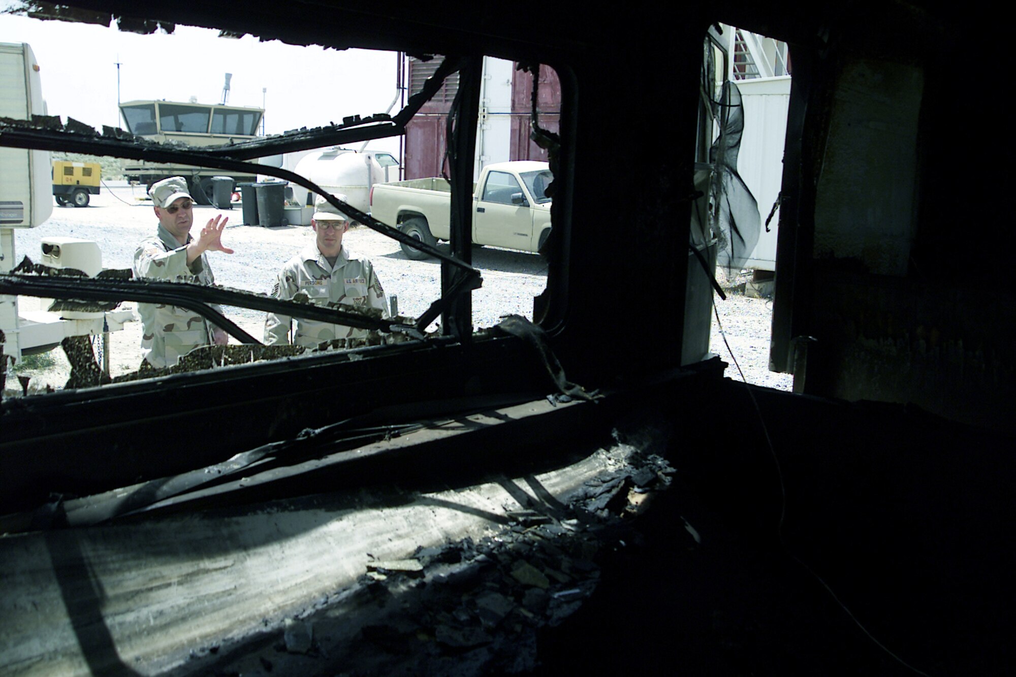 SOUTHWEST ASIA -- Tech. Sgt. Jerry Theriot (left) and Master Sgt. Harold Persons examine the burned out wreckage of a trailer that recently caught fire at a forward-deployed location.  Both Airmen are assigned to the 386th Expeditionary Civil Engineer Squadron's fire department.  Sergeant Theriot is the chief of fire prevention and is deployed from the 4th Civil Engineer Squadron at Seymour Johnson Air Force Base, N.C.  Sergeant Persons is the assistant chief of fire department operations and is deployed from the 97th CES at Altus AFB, Okla.  (U.S. Air Force photo by Capt. Tom Knowles)