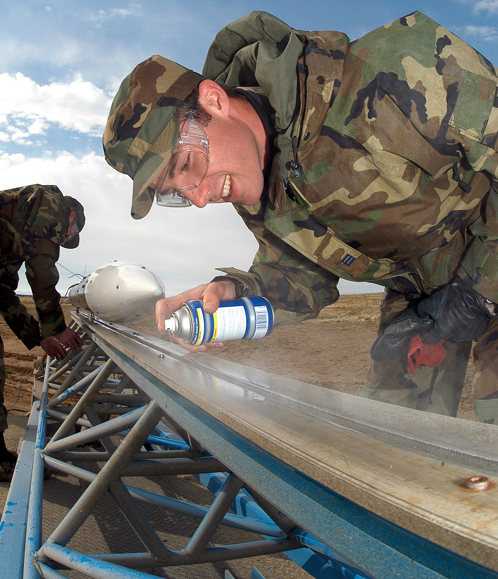 FORT CARSON, Colo. -- Cadet 1st Class Chris Nations sprays lubricant on the launch track before the rocket he and 17 other cadets built for a class project is fired.  U.S. Air Force Academy cadets taking Astronautical Engineering 452/453 Rocket Engineering classes completed their project April 25 by successfully firing the 11.5-foot tall, 7-inch diameter projectile from the Pinon Maneuver area here. (U.S. Air Force photo by Tech. Sgt. James A. Rush)