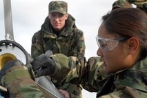FORT CARSON, Colo. -- Cadet 1st Class Manessa Catuncan tightens bolts on the exterior casing of a rocket she and 17 other cadets built as part of a class project.  U.S. Air Force Academy cadets taking Astronautical Engineering 452/453 Rocket Engineering classes completed their project April 25 by successfully firing the 11.5-foot tall, 7-inch diameter projectile from the Pinon Maneuver area here.  (U.S. Air Force photo by Tech. Sgt. James A. Rush)