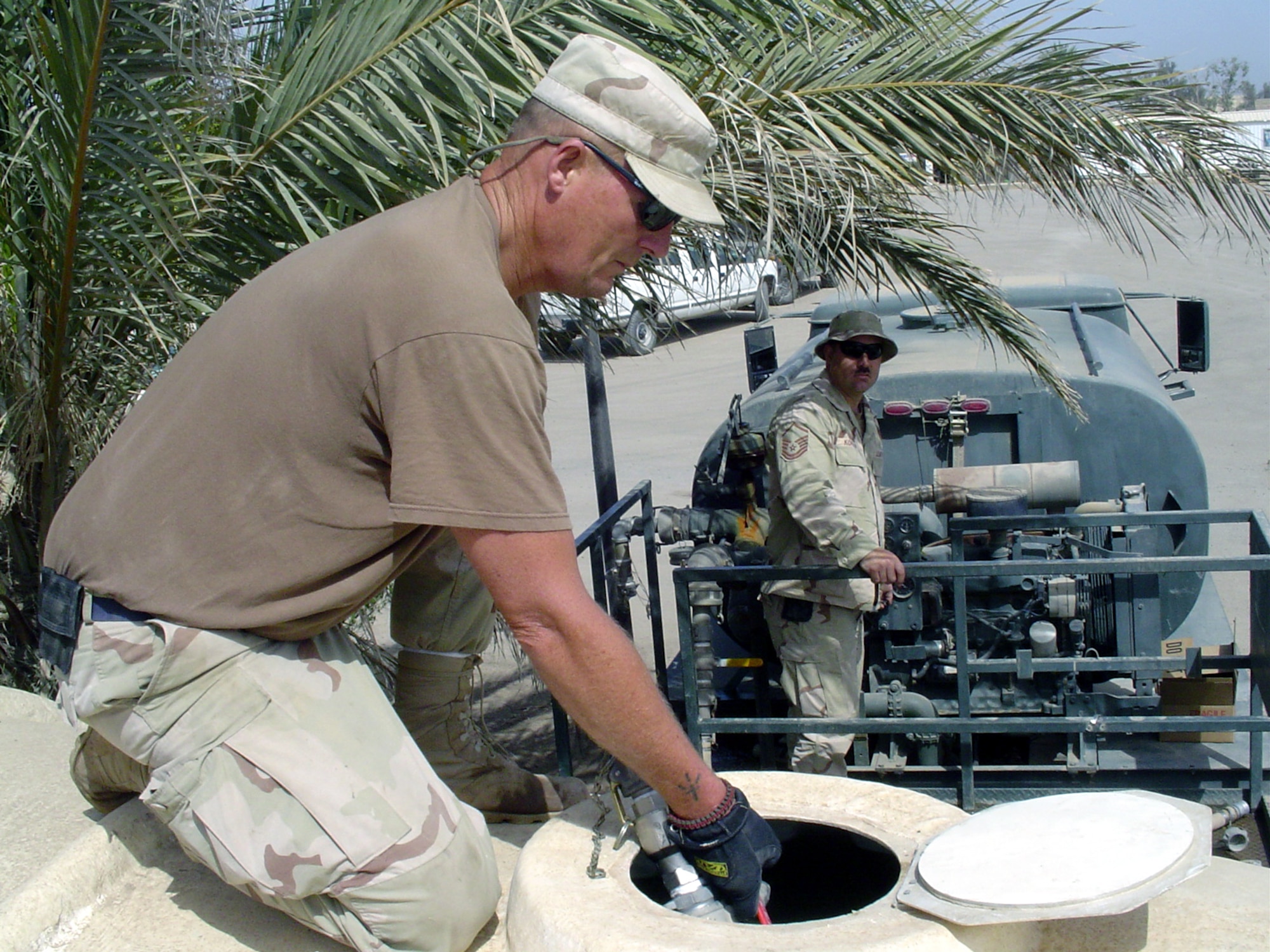 BAGHDAD, Iraq -- Staff Sgt. Brent Blankenship fills a water reservoir while Master Sgt. Bill Kopfman runs the pump on a portable water tanker.  Both Airmen are assigned to the 447th Expeditionary Civil Engineer Squadron here.  (U.S. Air Force photo by Master Sgt. Sean E. Cobb)