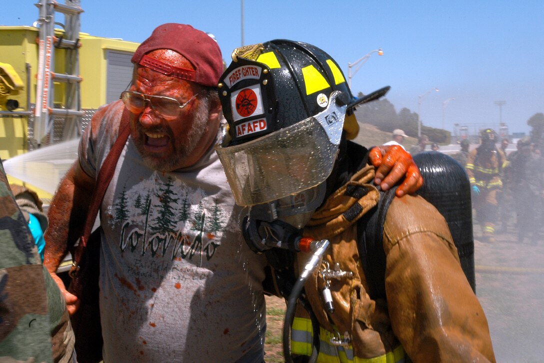 U.S. AIR FORCE ACADEMY -- An academy firefighter helps an "accident victim" through initial decontamination during a terrorist attack exercise here April 27.  The scenario presented academy response forces with a combined explosive and chemical threat during a football game.  Academy police, fire, medical and other services work with local agencies to complete a coordinated crisis response.  (U.S. Air Force photo by Joel Strayer)