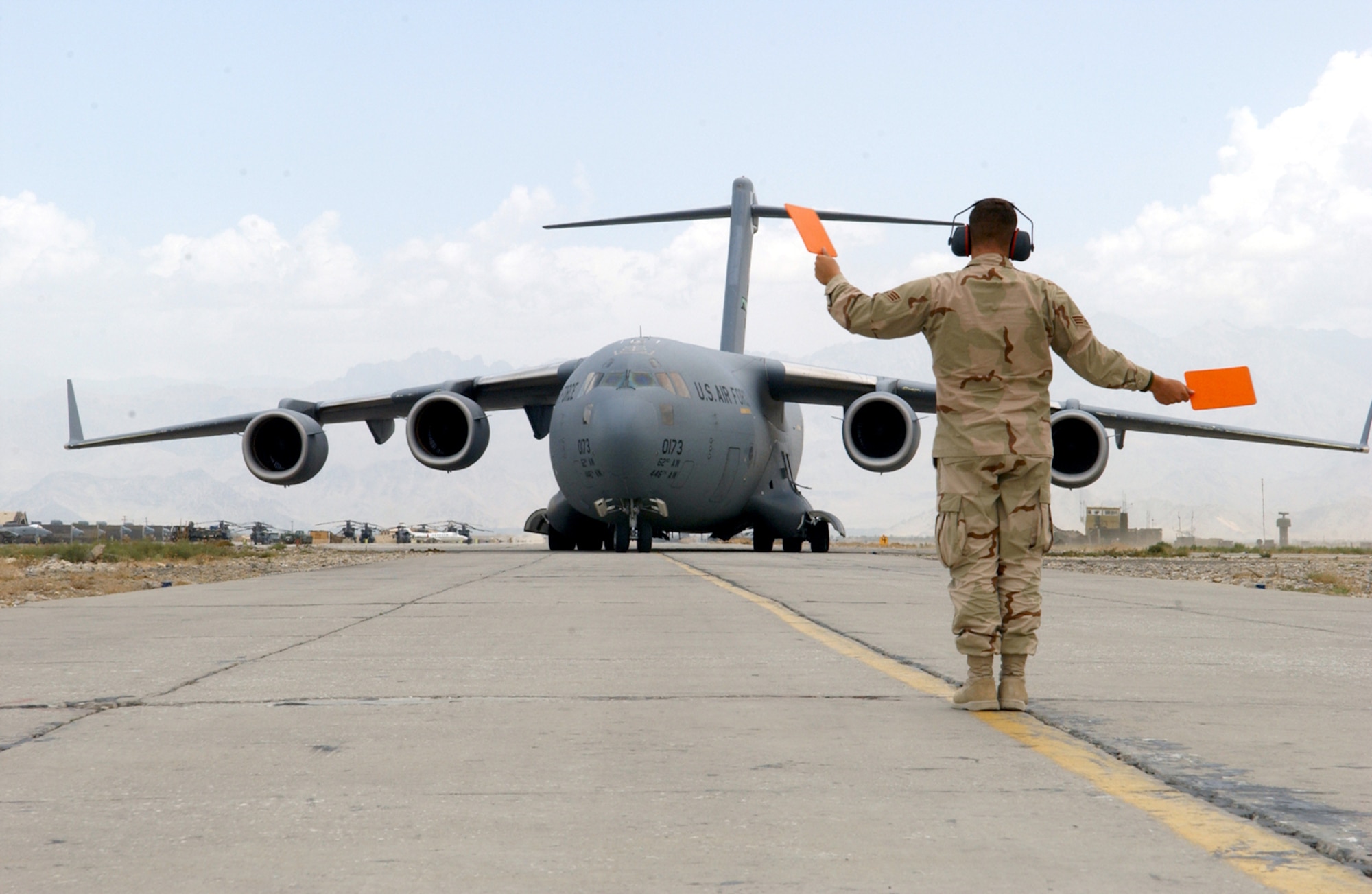 BAGRAM AIR BASE, Afghanistan -- Senior Airman George Bronson guides a C-17 Globemaster IIII crew to a parking spot on the flightline here.  Airman Bronson is a 455th Expeditionary Logistics Readiness Squadron transient-alert team member deployed from Little Rock AFB, Ark. The transient-alert Airmen handle an average of 14 aircraft each 12-hour shift. (U.S. Air Force photo by Master Sgt. Andrew Gates)