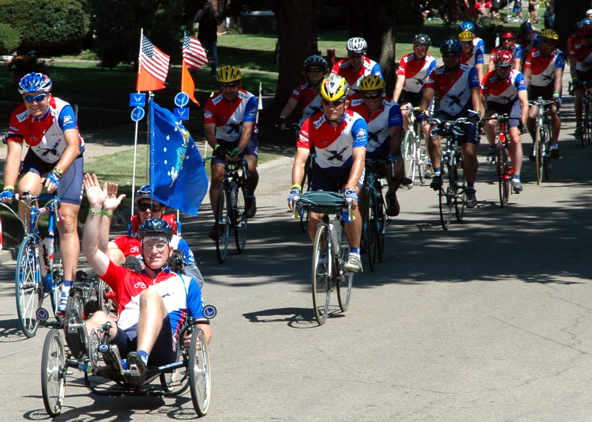 CLINTON, Iowa -- Tech. Sgt. Brad Whitmill of Offutt Air Force Base, Neb., and Tech. Sgt. Joel Weatherhead of Kunsan Air Base, Korea, wave to bystanders here at the end of the 32nd Des Moines Register's Great Bicycle Ride Across Iowa.  The cyclists were among the more than 100 members of Team Air Force and almost 10,000 other riders in the weeklong, 490-mile ride across the state.  Team Air Force rode into town at high noon July 31 in a two-column formation, a RAGBRAI tradition.  (U.S. Air Force photo by Lisa Adamson)