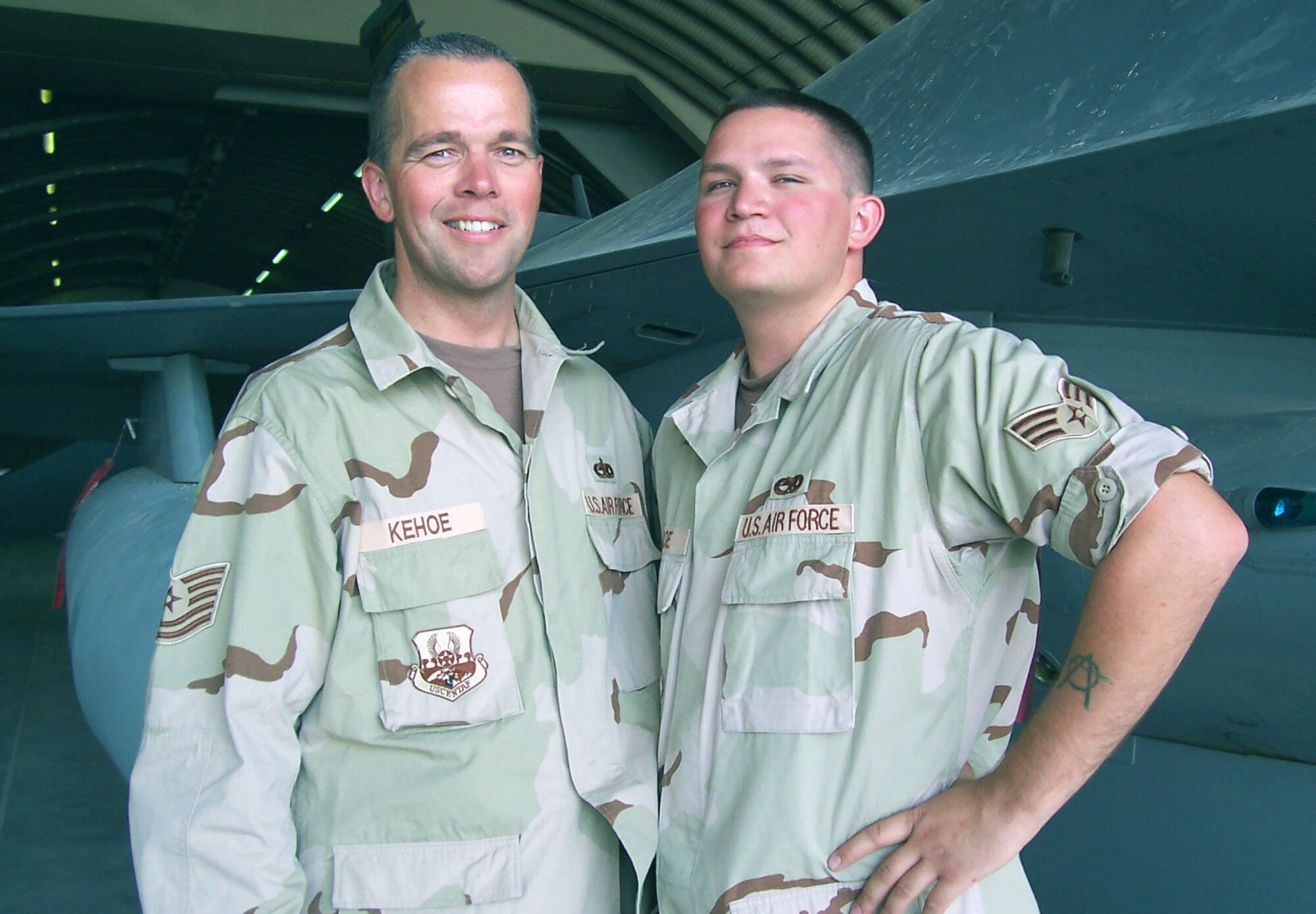 SOUTHWEST ASIA -- Tech. Sgt. James Kehoe (left) and his son, Senior Airman Travis Kehoe, are deployed together here supporting operations Enduring Freedom and Operation Iraqi Freedom.  They are Airmen with the Vermont Air National Guard's 158th Fighter Wing.  The memory of Marine Cpl. Mark Evnin, a family friend who was killed in action last year, is what puts the fire in their fight.  (U.S. Air Force photo by Staff Sgt. Colleen Bushnell)  