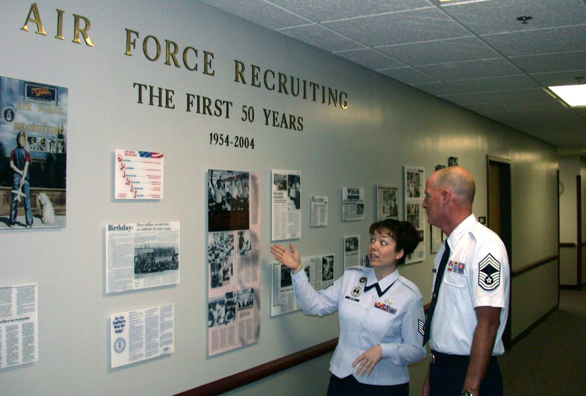 LACKLAND AIR FORCE BASE, Texas -- Recruiter instructor Tech. Sgt. Lynn Bryan shows Chief Master Sgt. Gerald Thayer the Air Force Recruiting School's redecorated entrance hallway.  Sergeant Bryan used newspaper and magazine stories covering the school's 50-year history.  Chief Thayer is the school's commandant.  (U.S. Air Force photo by James Coburn)