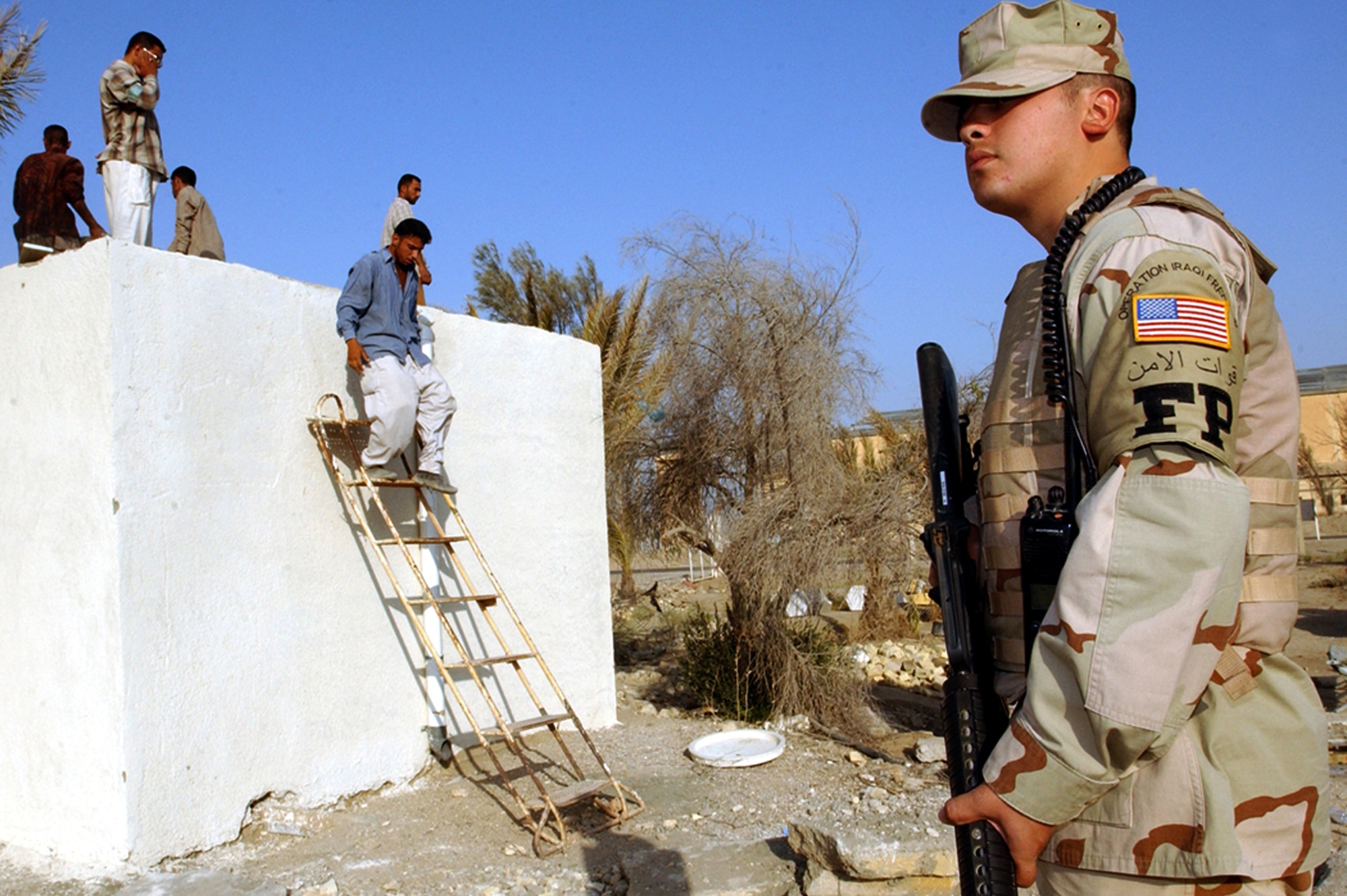 TALLIL AIR BASE, Iraq -- Senior Airman Matthew Diaz watches local-national workers while they renovate a building here.  Airman Diaz is one of about 50 Airmen deployed here to serve as an escort for the 407th Expeditionary Civil Engineer Squadron's force protection flight.  (U.S. Air Force photo by Staff Sgt. Craig Clapper)