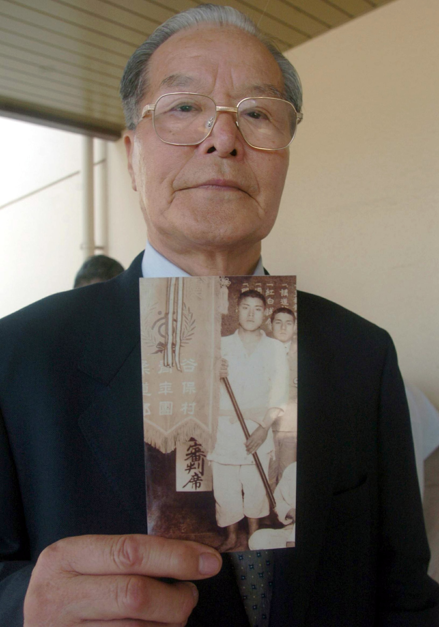 YOKOTA AIR BASE, Japan -- Manshichi Saeki holds a picture of his older brother, Ippei, a Japanese soldier who died fighting against American forces during World War II.  A Japanese flag signed and given to the warrior by his friends and relatives before he died was presented to Mr. Saeki during a ceremony here Aug. 6.  (U.S. Air Force photo by Master Sgt. Val Gempis)