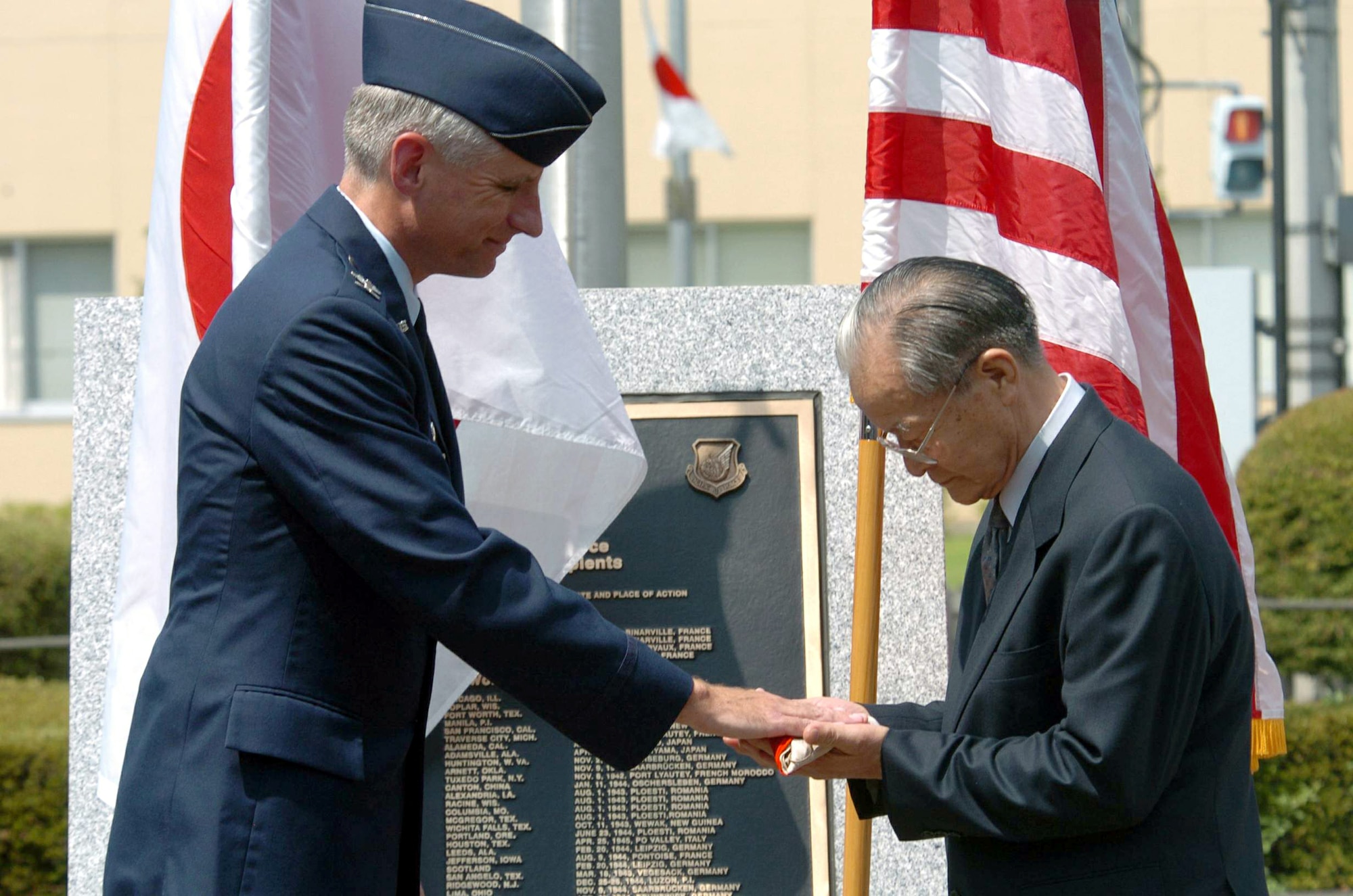 YOKOTA AIR BASE, Japan -- Col. Mark Schissler (left) returns a Japanese flag to Manshichi Saeki during a ceremony here Aug. 6.  The flag belonged to Mr. Saeki's older brother who died fighting against American forces during World War II.  Colonel Schissler is commander of the 374th Airlift Wing.  (U.S. Air Force photo by Master Sgt. Val Gempis)