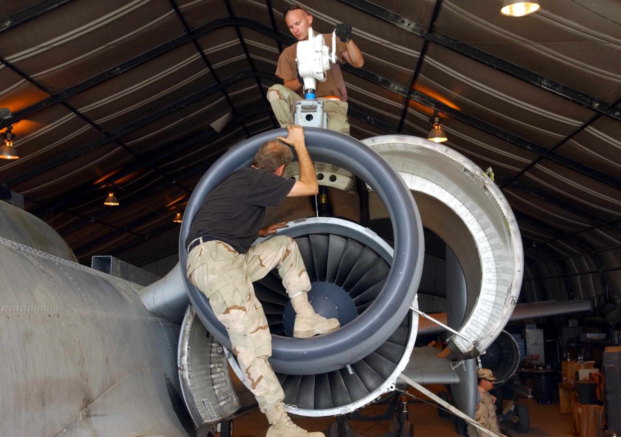 BAGRAM AIR BASE, Afghanistan -- Staff Sgt. Eric Lundberg (top) and Tom Ross maneuver an A-10 Thunderbolt II engine into place during an engine swap.  Both men are deployed as part of the 354th Expeditionary Aircraft Maintenance Squadron.  (U.S. Air Force photo by Master Sgt. Andrew Gates)
