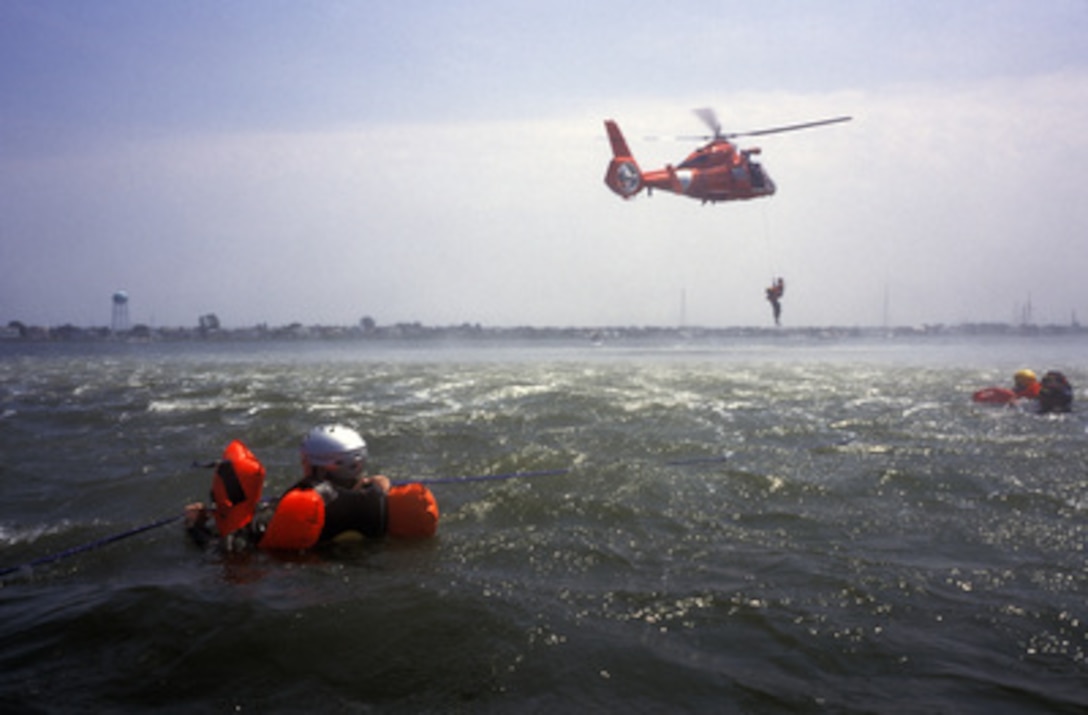 An HH-65A Dolphin helicopter from the Coast Guard Air Station Atlantic City, N.J., lowers Petty Officer 3rd class Zee Lee to pick up aircrew members who are participating in water survival training as part of aircrew certification in Long Beach Island, N.J., on July 29, 2004. 
