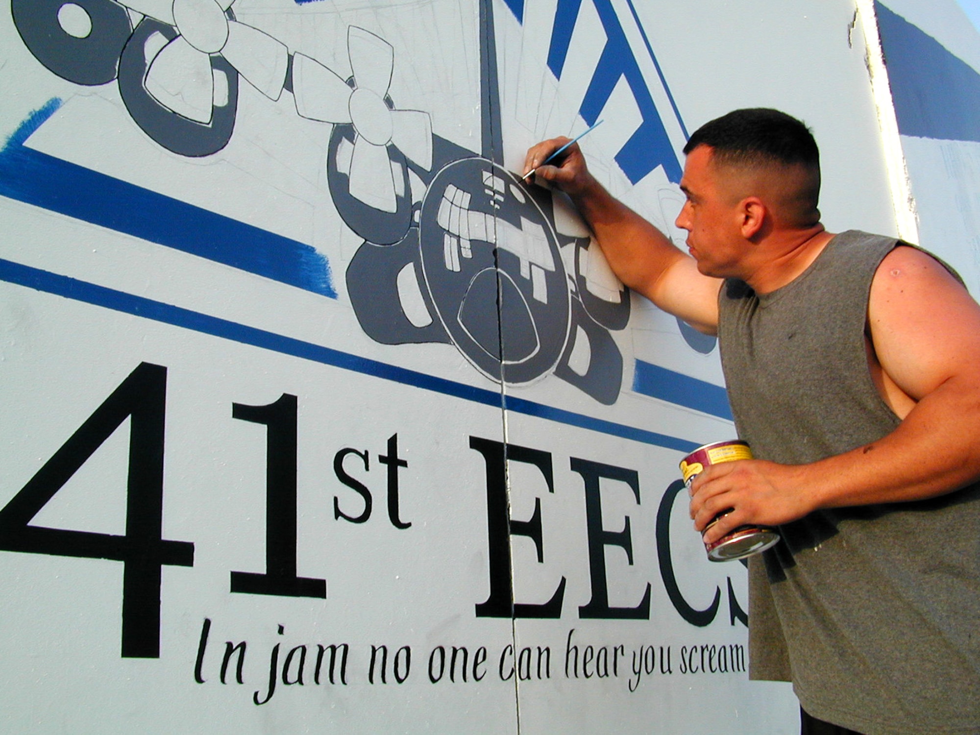 OPERATION ENDURING FREEDOM -- Staff Sgt. John Alsvig touches up his painting of an EC-130H on a mural documenting his unit's arrival on the frontlines of the war on terrorism. Alsvig is a fuels system specialist from the 41st Expeditionary Electronic Combat Squadron.  (U.S. Air Force photo by Master Sgt. Darrell Lewis)