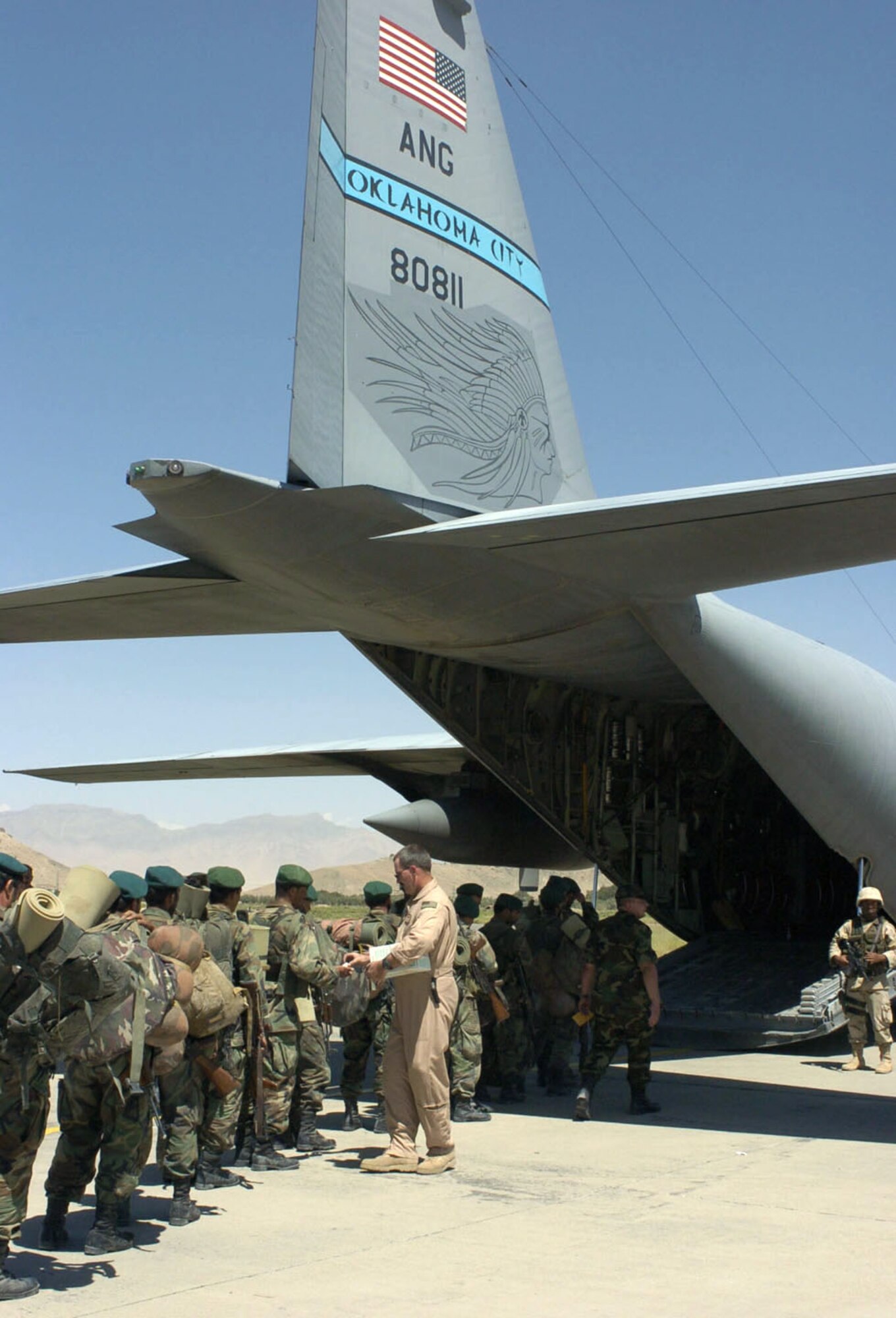 KABUL, Afghanistan -- Tech. Sgt. Tim Watts passes out ear plugs to Afghan soldiers waiting to board a C-130 Hercules on Aug. 15 at Kabul International Airport here.  The Oklahoma Air National Guard aircraft and crew helped airlift several Afghan battalions to Shindand to retake control of government property seized as a result of factional fighting in the area.  Sergeant Watts is an Oklahoma ANG C-130 aircrew member.  (U.S. Air Force photo by Master Sgt. Ann Bennett)