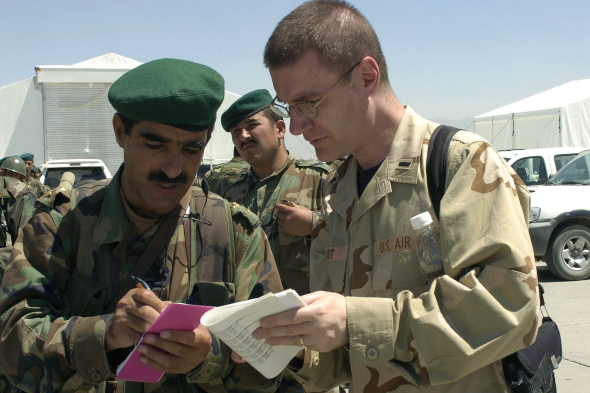KABUL, Afghanistan -- First Lt. John Faust coordinates with an Afghan soldier about the number of soldiers going out on the next C-130 Hercules to Shindand National Airport on Aug. 15.  The U.S. Air Force is helping to airlift several Afghan battalions to Shindand to retake control of government property seized as a result of factional fighting in the area.  Lieutenant Faust is an operations watch officer for Combined Forces Command-Afghanistan in Kabul.  (U.S. Air Force photo by Master Sgt. Ann Bennett)