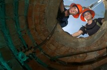DAVIS-MONTHAN AIR FORCE BASE, Ariz. -- Airmen 1st Class Chad Wolfe and Christina Holyoke help guide a sewer camera into a manhole to help them troubleshoot a plumbing problem they cannot get to on their own.  This camera will send a video to a monitor so the plumbers on the outside will be able to determine the problem.  Both Airmen are utilities apprentices with the 355th Civil Engineer Squadron here.  (U.S. Air Force photo by Staff Sgt. Lanie McNeal)