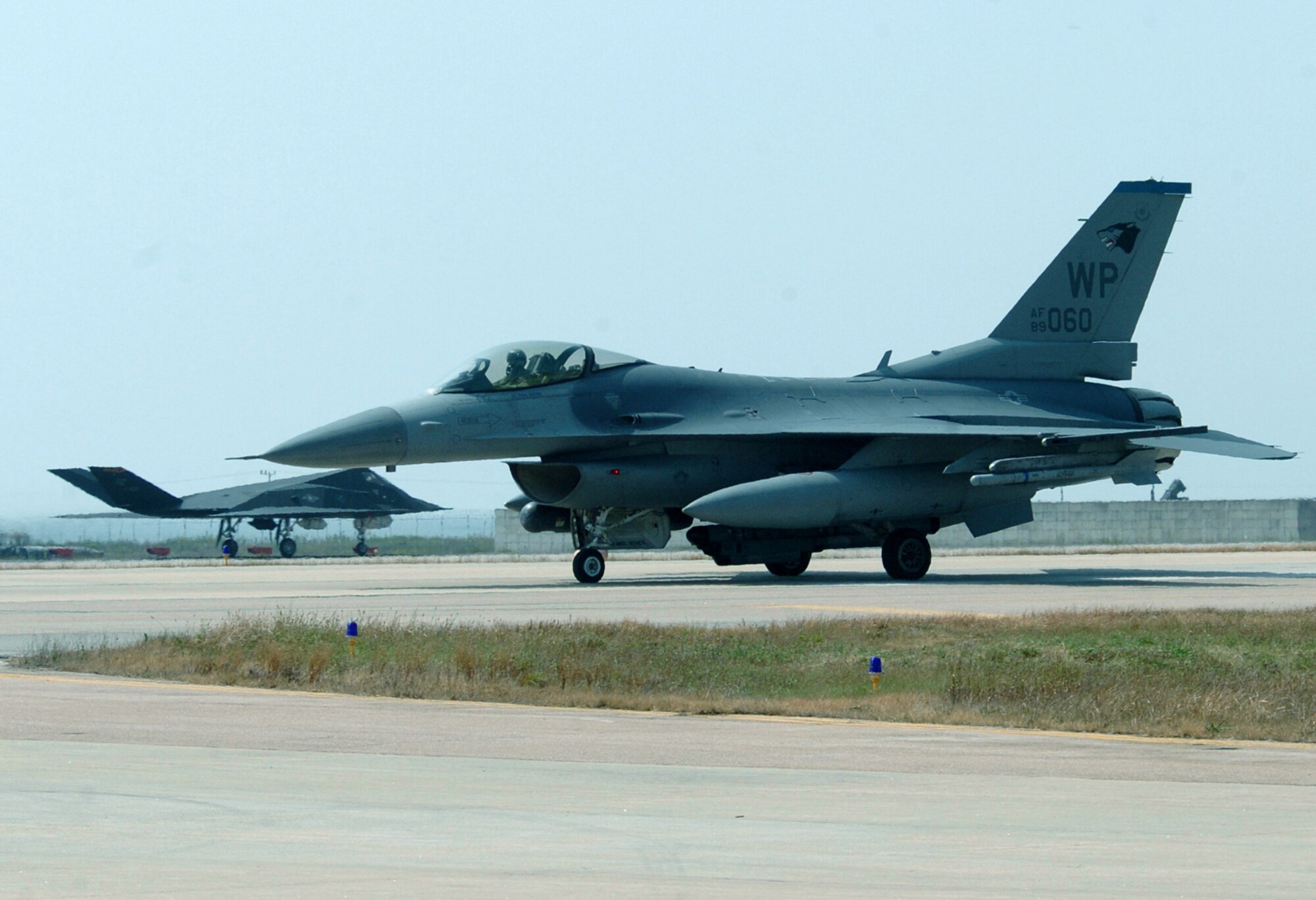 KUNSAN AIR BASE, South Korea -- An F-16 Fighting Falcon (foreground) from the 8th Fighter Wing here and an F-117 Nighthawk from the 49th Fighter Wing at Holloman Air Force Base, N.M., share the taxiway.  About 300 Airmen from Holloman are currently deployed here supporting operations in the Pacific region.  (U.S. Air Force photo by Master Sgt. Val Gempis)