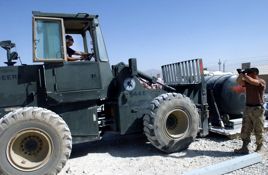 BAGRAM AIR BASE, Afghanistan -- Senior Airman Michael Spera (in forklift) moves a liquid-oxygen storage tank from the traffic management office storage area to a holding area, while Senior Airman Timothy Grasso guides him.  They are assigned to the 455th Expeditionary Logistics Readiness Squadron here.  Airman Spera is from Minot Air Force Base, N.D., and Airman Grasso is from Yokota Air Base, Japan.  (U.S. Air Force photo by Master Sgt. Andrew Gates)