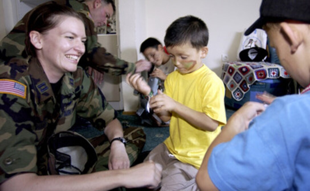 Air Force Capt. Farrah Newman plays with some children at their Sarajevo orphanage during Operation Smile at Camp Butmir, Bosnia, on Aug. 8, 2004. Operation Smile is a Stabilization Force volunteer program to provide moral support to orphaned children in Sarajevo by placing soldiers and orphaned children together in fun activities. 