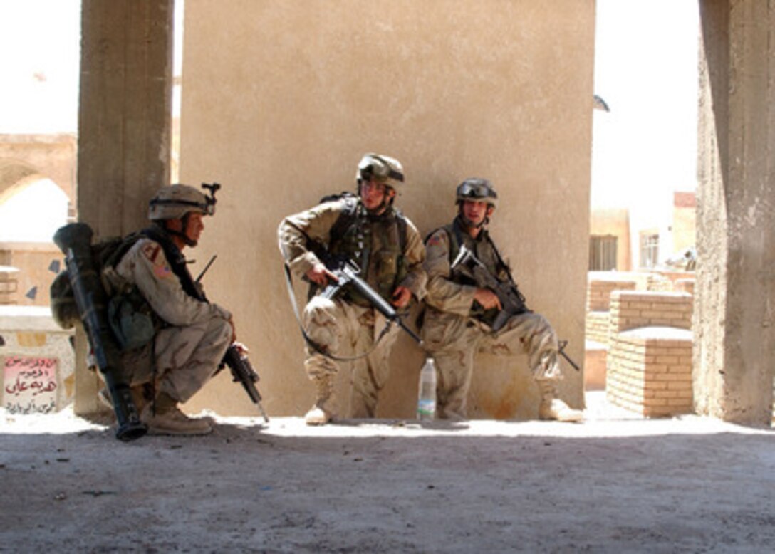 U.S. Army soldiers take cover behind a wall in a cemetery outside of An Najaf, Iraq, before moving forward to search through the mausoleums, tombs and catacombs on Aug. 10, 2004 for weapons caches, improvised explosive devices, and anti-Iraqi forces that might be hidden there. 