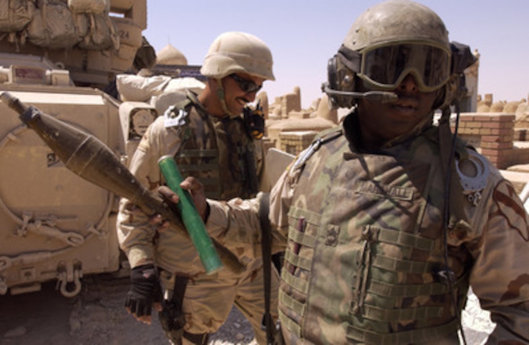Army Sgt. 1st Class Willie James Marshall (right) holds a rocket propelled grenade found in the An Najaf Cemetery, Iraq, on Aug. 15, 2004. U.S. Army soldiers are searching through the mausoleums, tombs and catacombs of the An Najaf cemetery for weapons caches, improvised explosive devices, and anti-Iraqi forces that might be hiding there. 