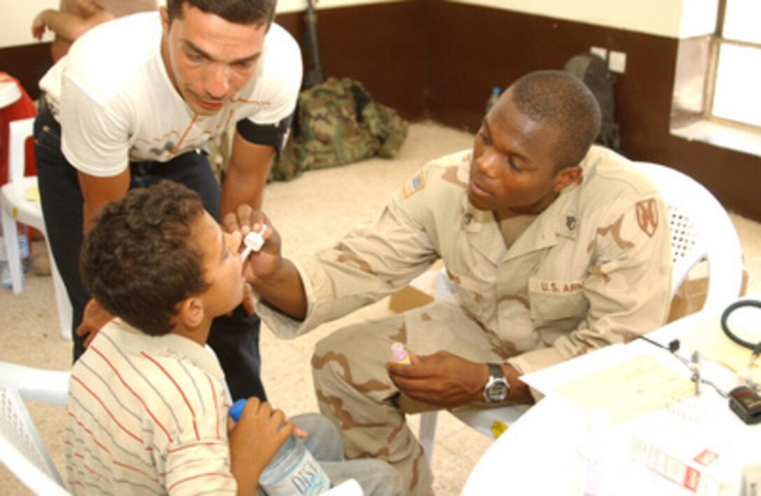 Army Staff Sgt. David Louis, from the 16th Military Police Brigade, treats an Iraqi boy on Aug. 17, 2004. Members of the 16th Military Police Brigade and 118th Medical Battalion, from the Ohio National Guard, set up a clinic for the day in Kshoum Hillan village outside of Baghdad International Airport, Iraq. The civil affairs members from the 16th MP Brigade also handed out toys and candy to children in the area. 