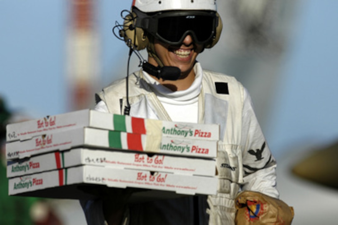 Petty Officer 2nd class Daniel Mina, of Detroit, Mich., delivers pizzas to eagerly waiting sailors aboard the USS Kitty Hawk (CV 63) on Aug. 14, 2004. Fleet Logistic Squadron 30, Detachment 5, flew the pizzas aboard from Kadena Air Force Base on Okinawa, Japan, during its daily delivery of mail, parts and personnel. The Kitty Hawk is participating in a scheduled deployment and supporting Summer Pulse 2004, a Navy exercise where seven aircraft carrier strike groups will learn new ways of operating, training, manning and maintaining their fleet. 