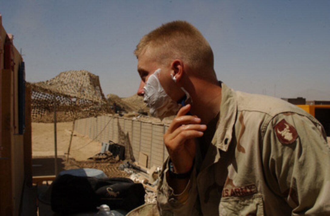 Army Spc. Brandon Dabb shaves outside at Tarin Kowt, Afghanistan, on Aug. 12, 2004. Dabb is attached to Task Force 168 which is providing security for the Tarin Kowt Forward Operating Base in support of Operation Enduring Freedom. 