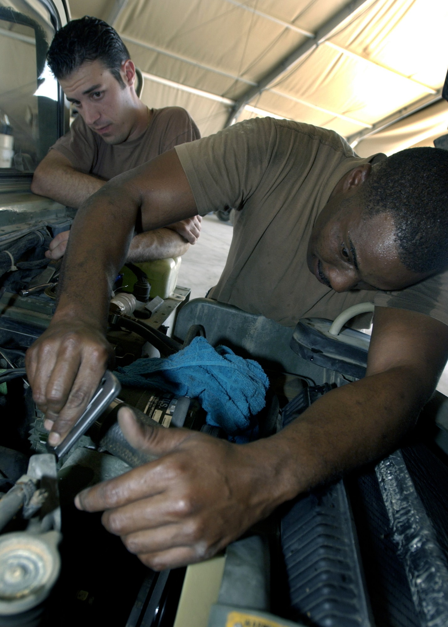 KARSHI-KHANBAD AIR BASE, Uzbekistan -- Staff Sgt. Jason Curra (left) and Tech. Sgt. William Underwood clean off a thermostat gasket on a Humvee.  The vehicle mechanics are assigned to the 416th Air Expeditionary Group here where, for the past two months, they have maintained a 100-percent vehicle in-commission rate.  (U.S. Air Force photo by Master Sgt. Scott Wagers)