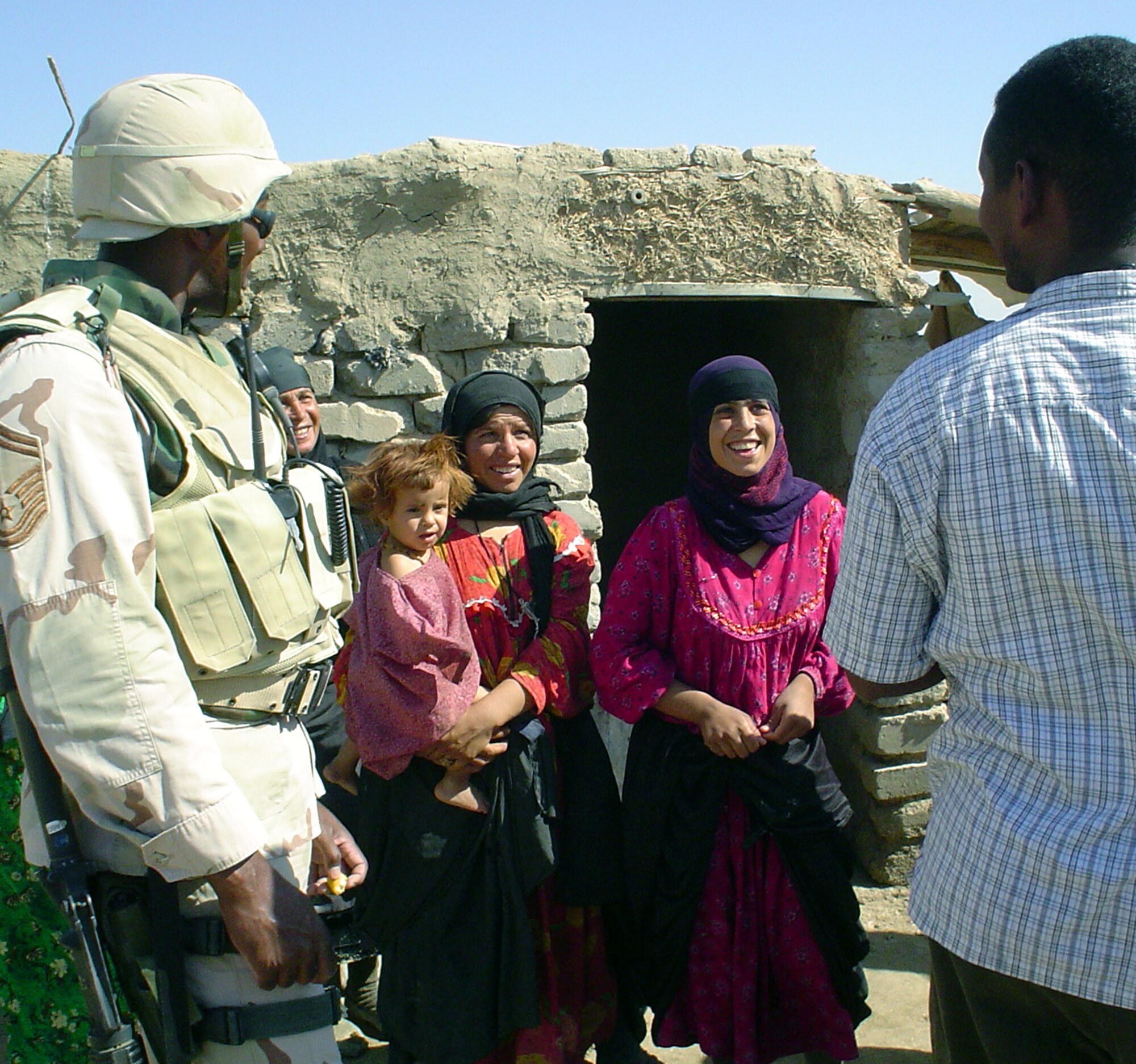 TALLIL AIR BASE, Iraq -- Senior Master Sgt. Don Dixon (left) and interpreter Badreldin Osman talk to a local family on the perimeter of the base during an Operation Reach Out visit.  Sergeant Dixon began the operation to establish a rapport with families living near the base.  He is the 407th Expeditionary Security Forces Squadron's operations superintendent.  (U.S. Air Force photo by Master Sgt. Debbie Aragon)