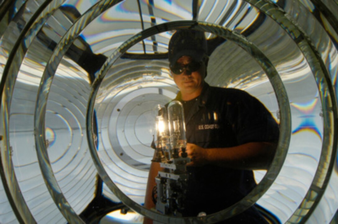 Petty Officer 3rd class Ryan Pritchard looks through the center of a Fresnel lens while testing a new lamp to ensure it is working properly in the lighthouse at Naval Air Station Pensacola, Fla., on Aug. 13, 2004. 