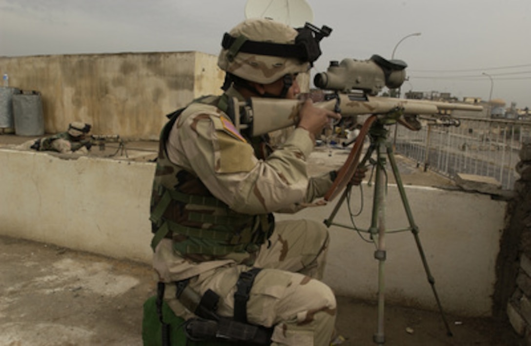 U.S. Army Spc. Chantha Bun (foreground) and Sgt. Anthony Davis (left) scan for enemy activity from an Iraqi police station in Mosul, Iraq, on Nov. 17, 2004. U.S. soldiers and Iraqi National Guard members secured the police station after attacks by insurgents. Bun and Davis are Bravo Company snipers assigned to 1st Battalion, 24th Infantry Regiment, 1st Brigade, 25th Infantry Division, Stryker Brigade Combat Team. 