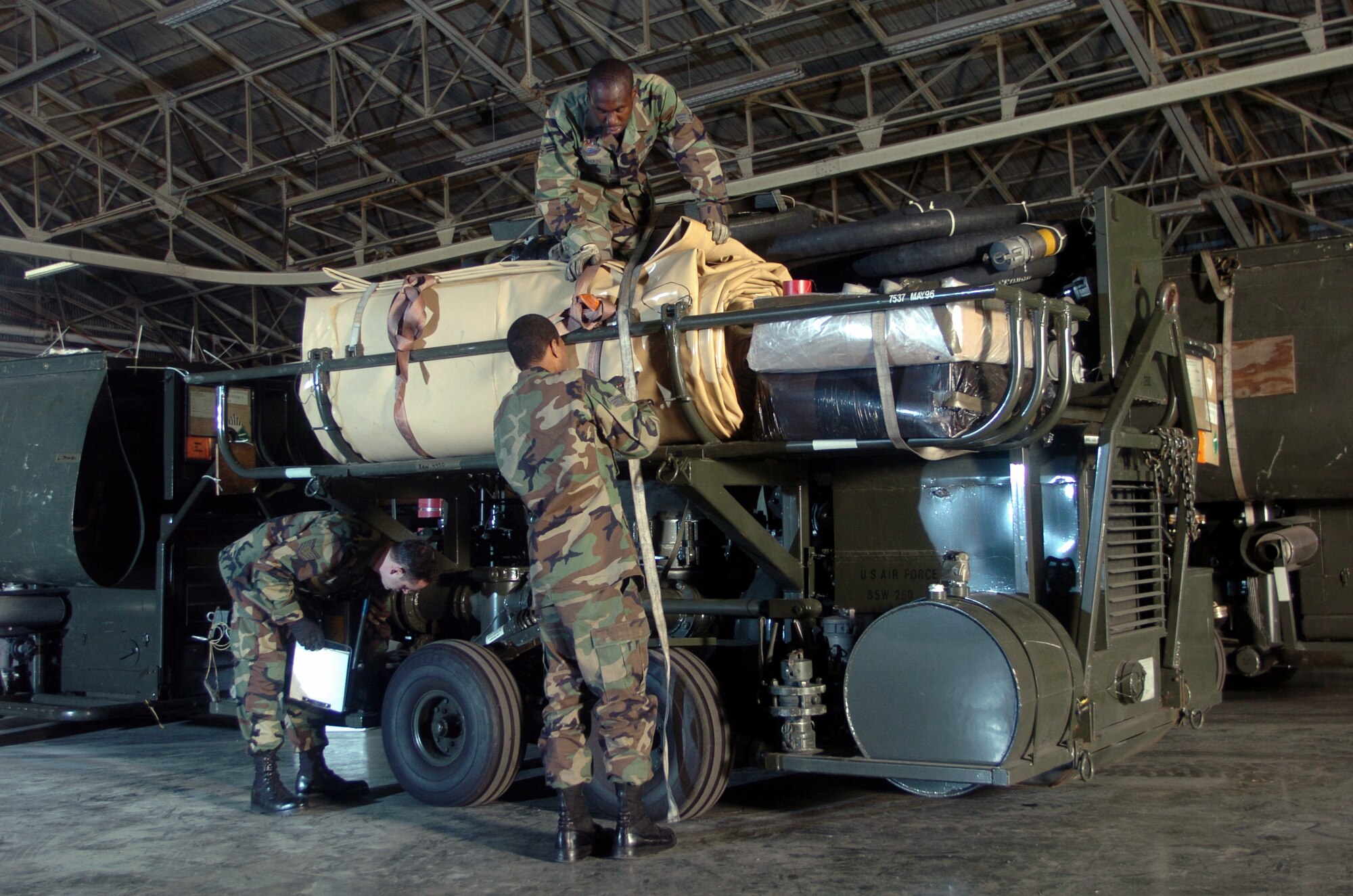 YOKOTA AIR BASE, Japan -- Tech. Sgt. Charles Egri (left), Senior Airmen David Cameron (top) and Dwayne Gooden inspect an R-14 air transportable hydrant refueling system during inspection here.  The R-14 can be airlifted or ground shipped anywhere in the world and made fully operational in a matter of hours.  Each unit contains a pump; two 50,000-gallon bladder tanks; and all the hoses, valves, and fittings necessary for operation.  The Airmen are assigned to the 374th Logistics Readiness Squadron's fuels mobility support equipment element.  (U.S. Air Force photo by Master Sgt. Val Gempis) 