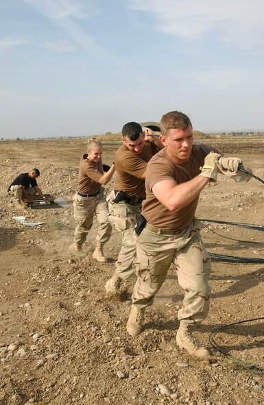 KIRKUK AIR BASE, Iraq -- (From left) Staff Sgt. Jose Olivares, Airman 1st Class Crystal Bryant, Senior Airman John Dowalgo and 2nd Lt. Joseph Plank pull fiber optic cables during a communications upgrade project here.  They are assigned to the 506th Expeditionary Communications Squadron.  (U.S. Air Force photo by Staff Sgt. Adrian Cadiz)