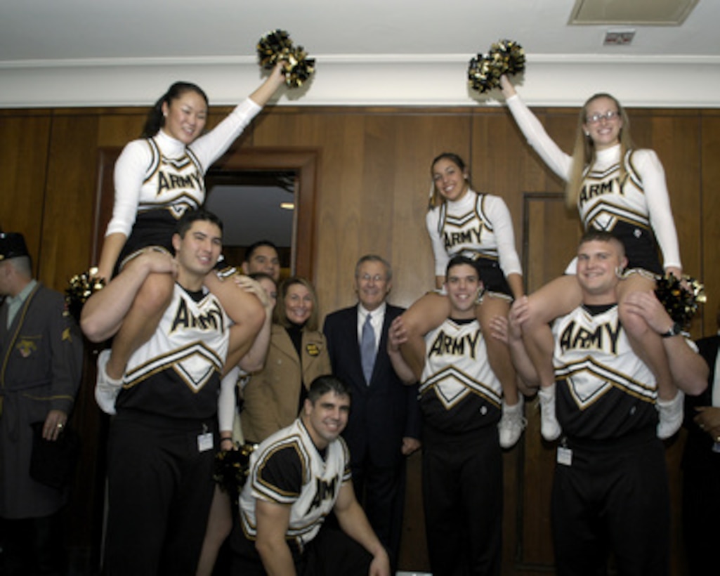 Secretary of Defense Donald H. Rumsfeld (center) is greeted outside his Pentagon office by the West Point Academy cheerleaders and band on Dec. 3. 2004. The cadets are promoting esprit de corps in the Pentagon for the upcoming Army/ Navy football game on Dec 4, 2004. 
