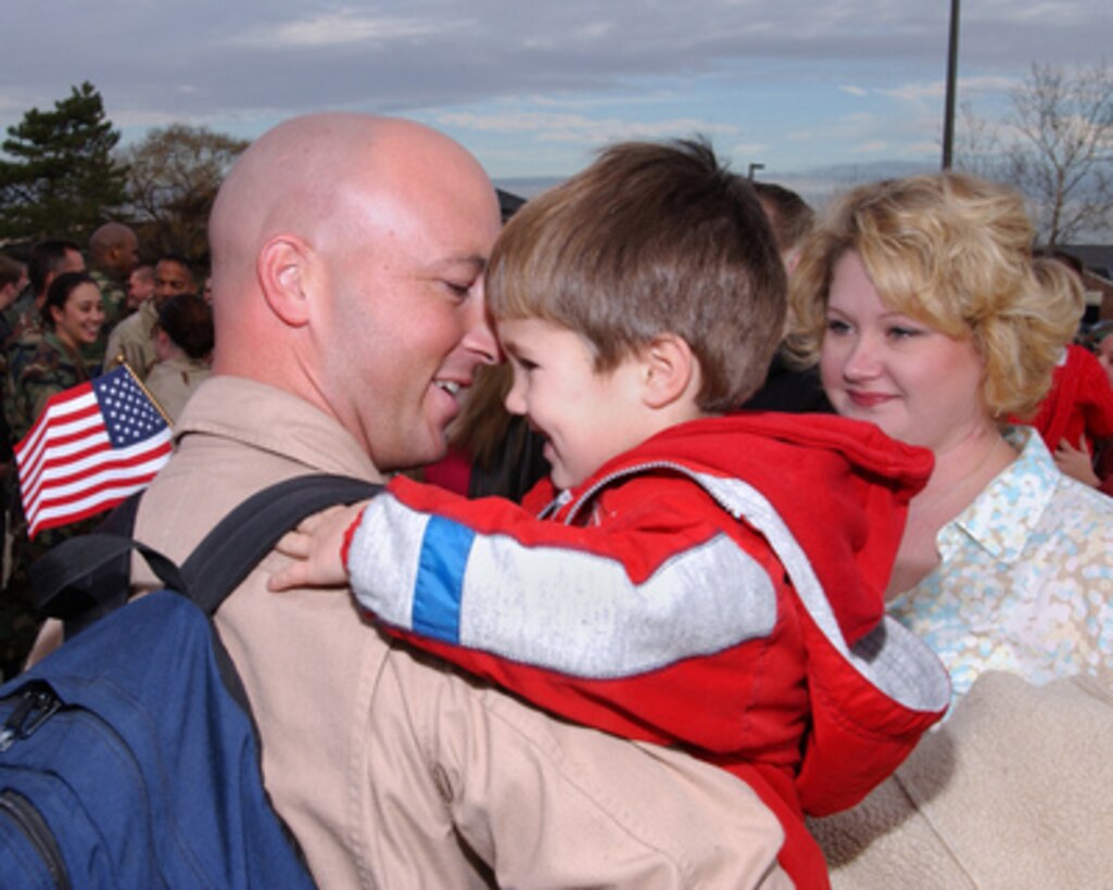 U.S. Air Force Capt. Jason Helton (left) holds his son Alexander while his wife Kerry looks on as he returns to McGuire Air Force Base, N.J., on Nov. 30, 2004. Helton is assigned as a pilot for the 32nd Air Refueling Squadron and is returning home from a 50-day deployment in Southeast Asia in support of Operation Iraqi Freedom. 