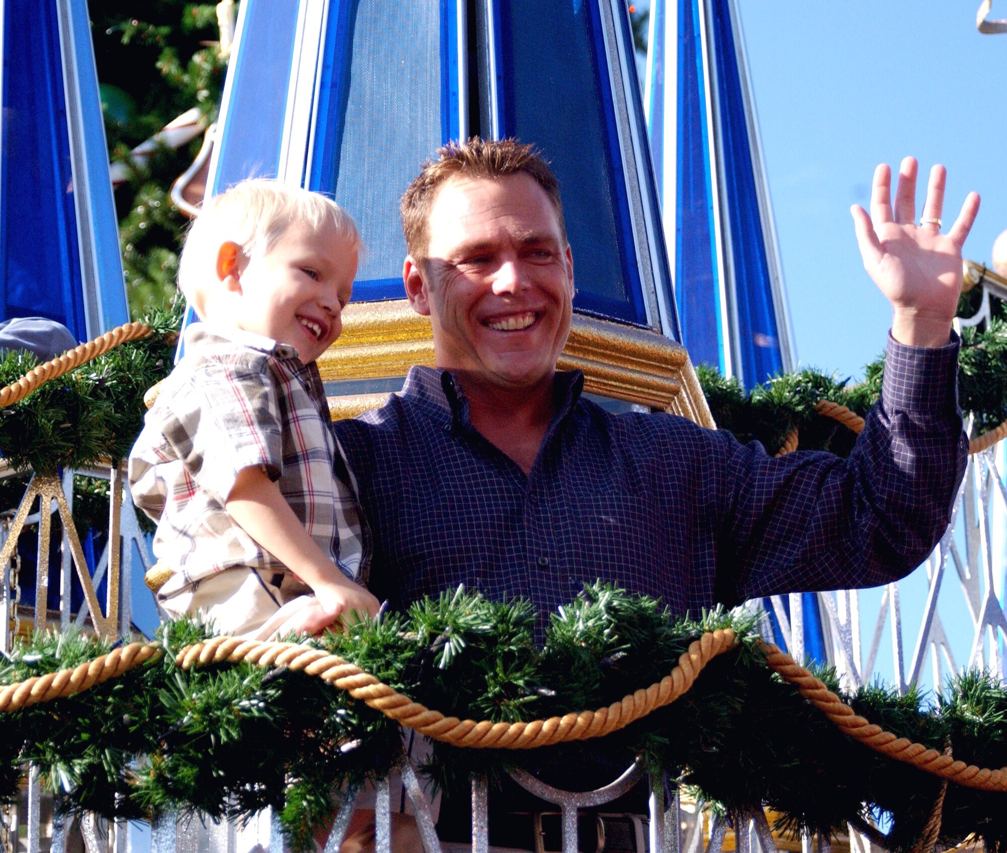 ORLANDO, Fla. -- Jim Craig and his son, Connor, wave to the crowd at Walt Disney World as they ride along on the military appreciation float.  Mr. Craig's wife, Maj. Adriane Craig, is deployed from Patrick Air Force Base, Fla., to Southwest Asia supporting Operation Iraqi Freedom.  (Courtesy photo)

