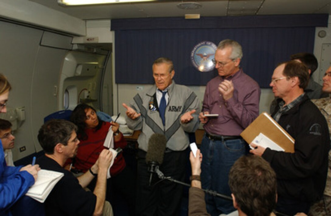 Reporters surround Secretary of Defense Donald H. Rumsfeld as he holds a press conference while in flight to Kuwait on Dec. 6, 2004. Rumsfeld will meet with the Kuwaiti leadership to thank them for their support in the global war on terror and Operation Iraqi Freedom. 