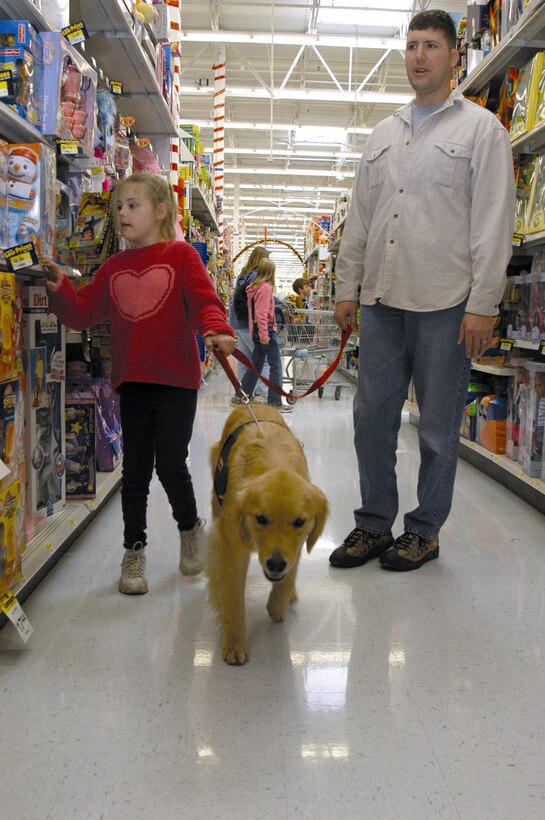 COLORADO SPRINGS, Colo. -- Jamie and her father, 1st Lt. Victor Rizzo walk through the toy aisle of a local department store with Berkley, a Canine Assistants service dog.  The Rizzos were awarded a service dog for 7-year-old Jamie, who is socially developed at a 2-year-old level. Canine Assistants trains golden retrievers and Labrador retrievers to assist people with physical and mental disabilities.  Lieutenant Rizzo is assigned to the 3rd Space Operations Squadron at nearby Schriever Air Force Base.  (U.S. Air Force photo by Senior Airman Mike Meares)