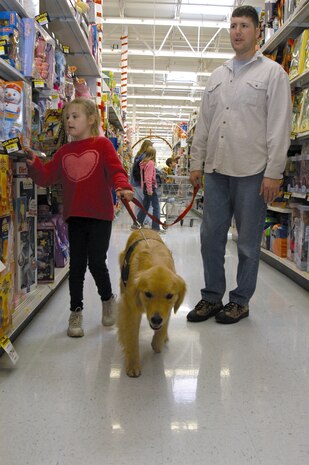 COLORADO SPRINGS, Colo. -- Jamie and her father, 1st Lt. Victor Rizzo walk through the toy aisle of a local department store with Berkley, a Canine Assistants service dog.  The Rizzos were awarded a service dog for 7-year-old Jamie, who is socially developed at a 2-year-old level. Canine Assistants trains golden retrievers and Labrador retrievers to assist people with physical and mental disabilities.  Lieutenant Rizzo is assigned to the 3rd Space Operations Squadron at nearby Schriever Air Force Base.  (U.S. Air Force photo by Senior Airman Mike Meares)
