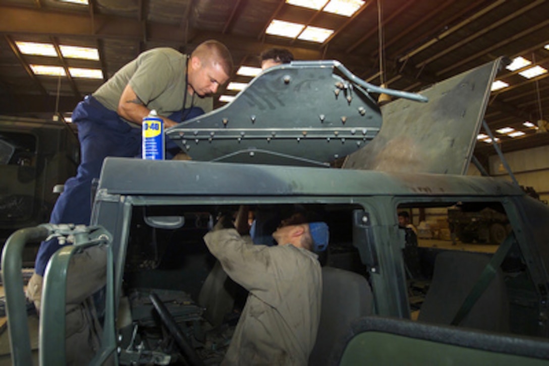 Civilian contractors install a gunner's shield atop a Humvee from the 24th Marine Expeditionary Unit at an armor installation facility in Kuwait on July 17, 2004. The gunner's shield is part of the up-armor being placed on the expeditionary unit's vehicles. Up-armor offers the Marines in the vehicle 360 degrees of protection. 