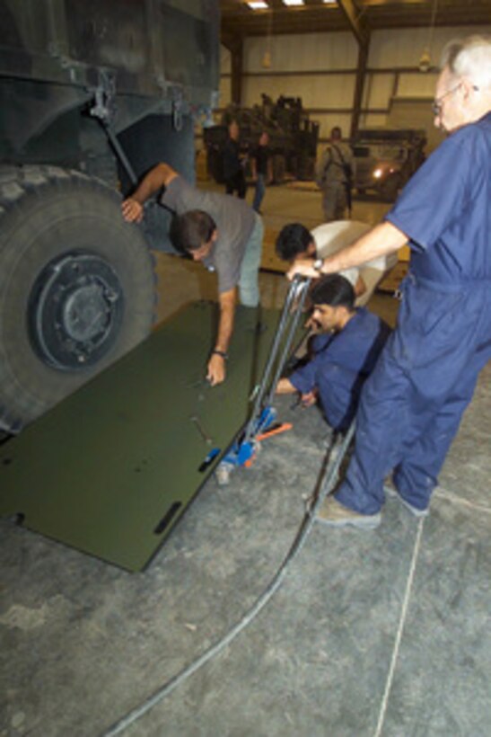 Civilian contractors prepare to install an up-armored side panel to a seven-ton truck at an armor installation facility in Kuwait on July 17, 2004. The side paneling is part of the up-armor being placed on 24th Marine Expeditionary Unit vehicles. 