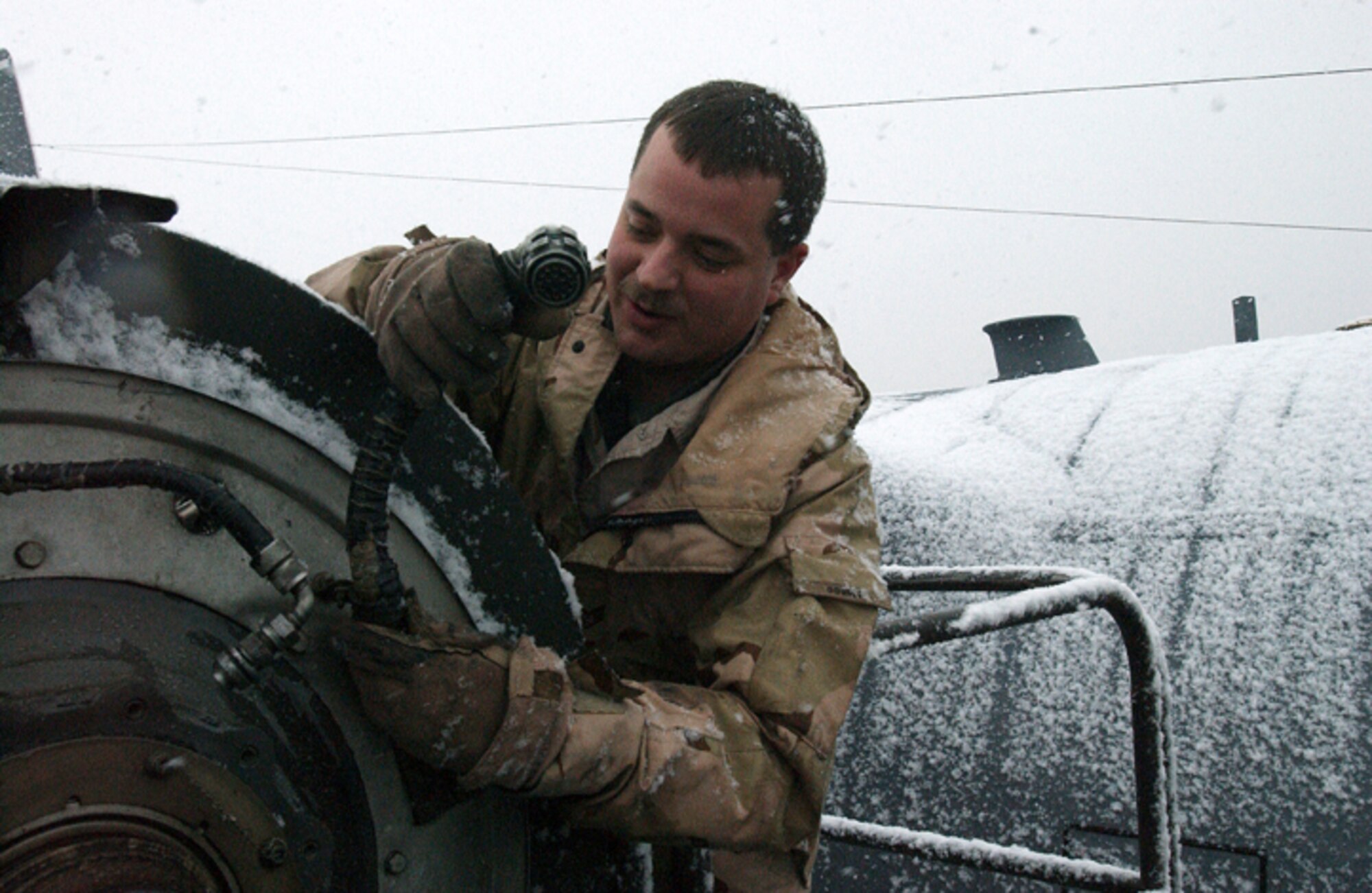 KARSHI-KHANABAD AIR BASE, Uzbekistan -- Staff Sgt. Michael Godbey changes a C-130 Hercules propeller in the snow here.  Because the base's maintainers have no hangars for maintenance, repairs must be done when and where they are needed.  Sergeant Godbey is a maintainer with the 416th Air Expeditionary Group here. Maintainers have helped the 744th Expeditionary Airlift Squadron maintain a 100 percent mission accomplishment rate for the past four months.  (U.S. Air Force photo by Senior Airman Matthew Rosine)