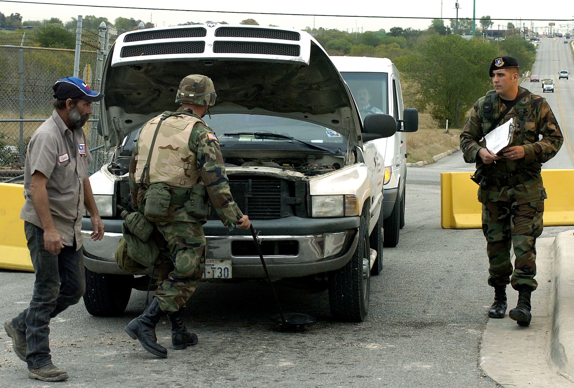 LACKLAND AIR FORCE BASE, Texas -- Army Specialist Ryan Moffenbier of the 4th Infantry Division out of Fort Hood, Texas, inspects a car here as Airman 1st Class Joshua Barnett of the 37th Security Forces Squadron here monitors the area during a quick reaction force exercise Dec. 8.   The mission was to provide a flexible and responsive unit to a specific region in the event of a domestic threat or incident. The exercise here trained the Soldiers to prepare for homeland defense missions. (U.S. Air Force photo by Staff Sgt. Derrick C. Goode)