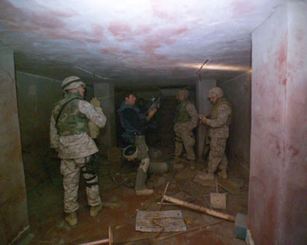U.S. Marines and news reporters gather information inside the bloody basement of the Islamic Resistance Center building in Fallujah, Iraq, on Dec. 2, 2004. The unmarked center for insurgent operations was one stop during a tour for media to different sites where reconstruction efforts are beginning after the November battle with insurgents. 