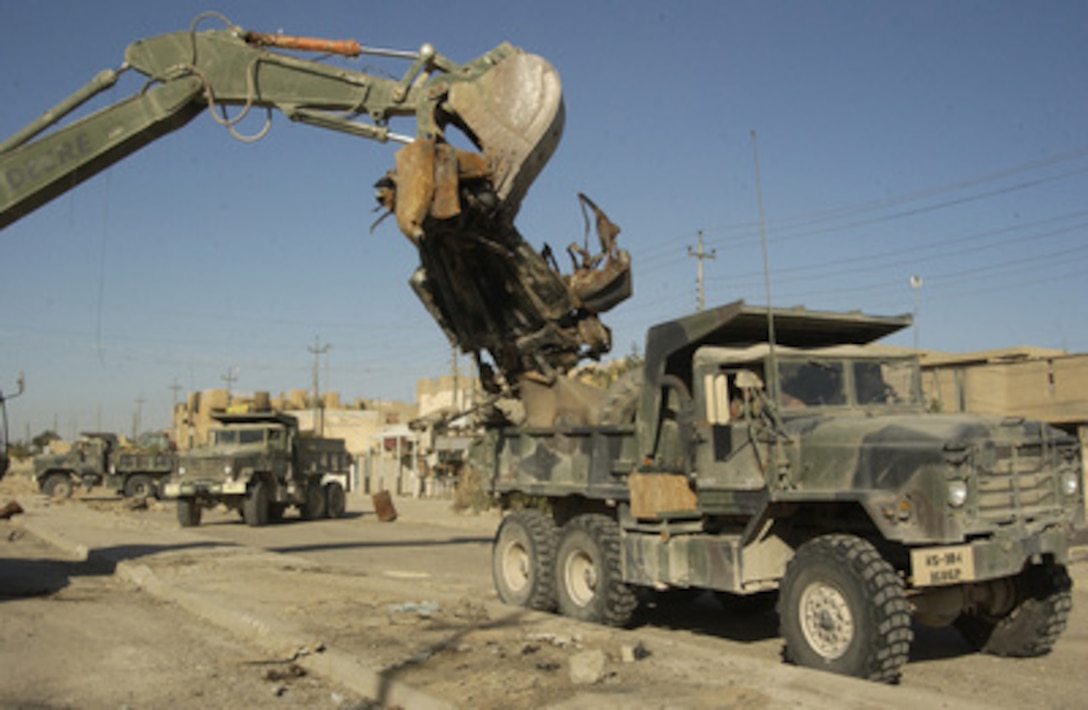 Engineers from the Oklahoma Army National Guard's 120th Engineering Combat Battalion clear debris, dirt and barriers from a mile of local streets near Route 10 in Fallujah, Iraq, on Dec. 5, 2004. The cleanup projects throughout Fallujah are to prepare the area for residents to return. 