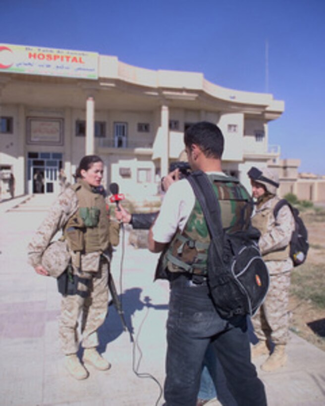 Arab news reporters conduct an on-site interview with 4th Civil Affairs Group Public Affairs Officer Maj. M. Naomi Hawkins in front of the Dr. Talib Al-Janabi Hospital in Fallujah, Iraq, on Dec. 2, 2004. The hospital was one stop during a tour for media to different sites where reconstruction efforts are beginning after the November battle with insurgents. 