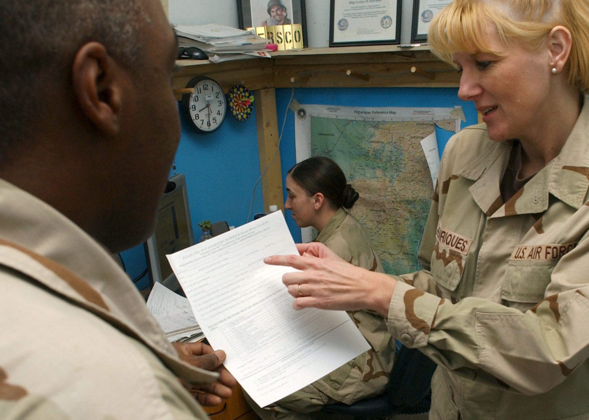 BAGRAM AIR BASE, Afghanistan -- Master Sgt. Carolyn Henriques helps a customer with paperwork while Airman 1st Class Angelique Smith enters deployment data on newly-arrived Airmen to the 455th Air Expeditionary Wing here.  The two-person Personnel Support for Contingency Operations team is deployed from Pope Air Force Base, N.C., supporting Operation Enduring Freedom.  (U.S. Air Force photo by Staff Sgt. Jennifer Lindsey)
