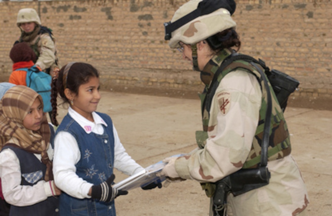 Army Maj. Elivira M. Brown (right) hands new school supplies to a student at the Al Rasheed School in Taji, Iraq, on Dec. 8, 2004. The school supplies were donated through Operation Iraqi Children which is a program that provides concerned Americans with the means to help the Iraqi people and help support the coalition's attempts to assist them. Brown is assigned to 443rd Civil Affairs Battalion. 
